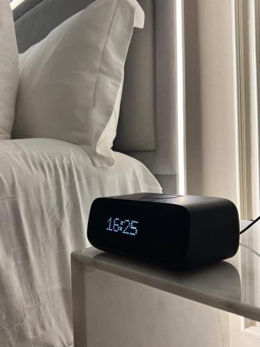 a clock sitting on a table next to a bed at The Key - Luxury Apartment in Doha