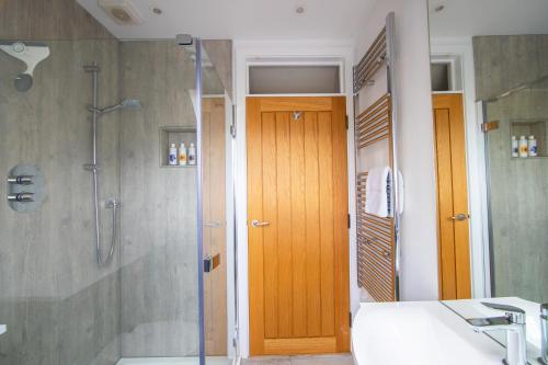 a bathroom with a shower and a wooden door at The Loft at The Little Elms in Motcombe