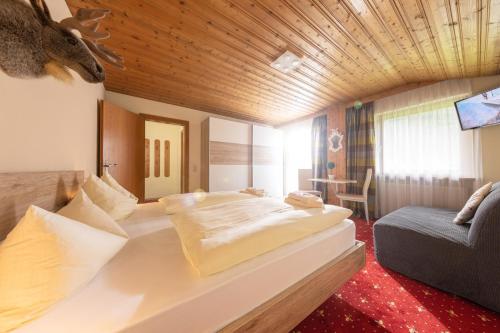 um quarto de hotel com uma cama grande e um sofá em T3 Gasthof Spullersee em Wald am Arlberg