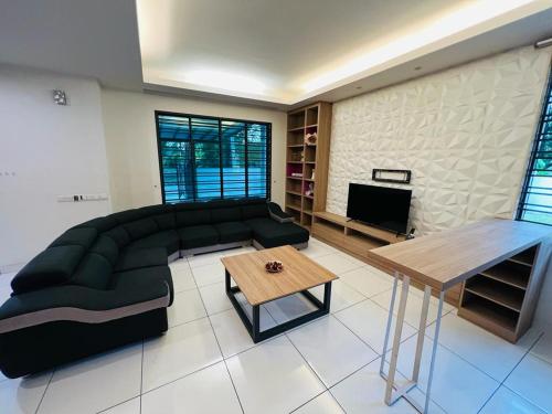 ein Wohnzimmer mit einem schwarzen Sofa und einem Tisch in der Unterkunft Kulai Lagenda Putra Corner House 古来公主城民宿 near JPO in Kulai