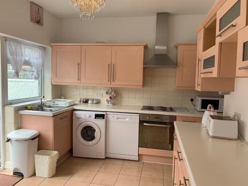 a kitchen with wooden cabinets and a washer and dryer at Starlight Self Service Accommodation in Leigh