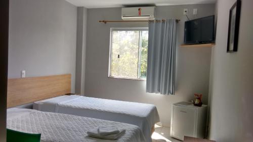 a bedroom with two beds and a television and a window at Flex Hotel in Canoinhas
