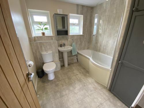 a bathroom with a tub and a toilet and a sink at Cosy bungalow in countryside village near coast in Pembroke