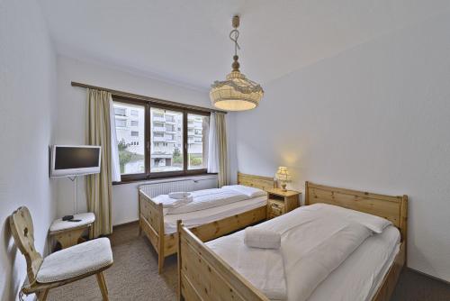 a bedroom with two beds and a tv and a window at Chesa Arlas - St. Moritz in St. Moritz