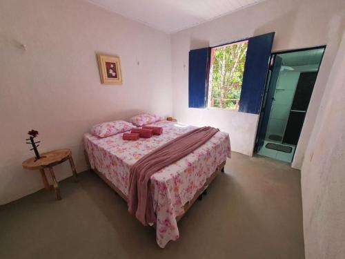 een slaapkamer met een bed met roze lakens en een raam bij Linda casa com banho natural em Guaramiranga in Guaramiranga