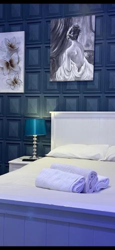 a bedroom with a white bed and a blue wall at Maria in London