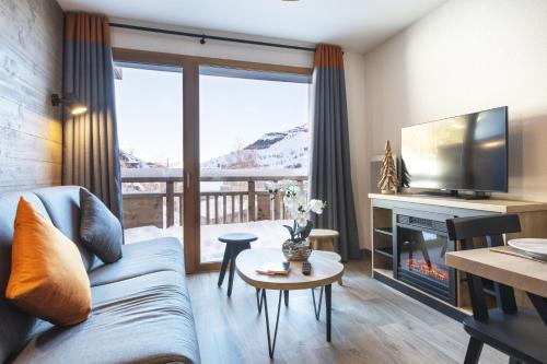 uma sala de estar com um sofá e uma televisão em Résidence Club MMV Les Clarines em Les Deux Alpes