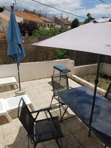 une terrasse avec une table, un parasol et des chaises dans l'établissement Le bon séjour, à Marseille