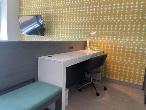 a bathroom with a sink and a desk and a mirror at The Orbit Hotel, Trademark Collection by Wyndham in Fairview Park