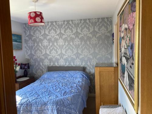 ein Schlafzimmer mit einem blauen Bett und einer Wand in der Unterkunft Caledonia House in Rosyth