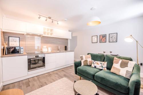 a living room with a green couch and a kitchen at Guildhall Street Apartment, Bury St Edmunds in Bury Saint Edmunds