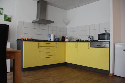 a kitchen with yellow cabinets and a stove at Guesthouse Casa Esperanza Basel in Basel