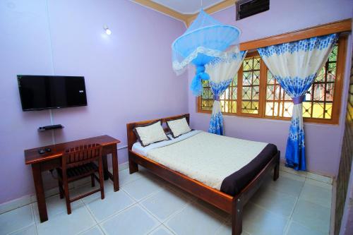 a bedroom with a bed and a desk and a television at Kenthill Guest House in Jinja