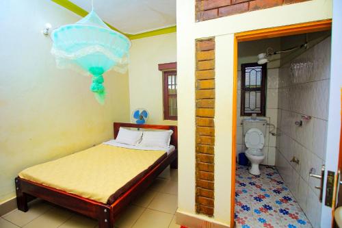 a bedroom with a bed and a bathroom with a toilet at Kenthill Guest House in Jinja