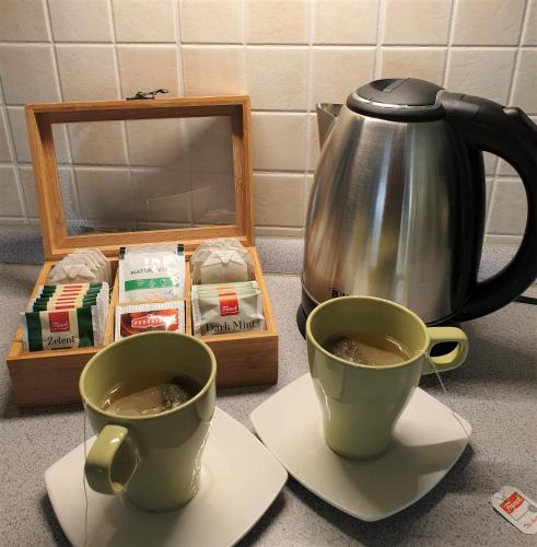 two cups of coffee and a tea kettle on a counter at Apartman Silvija in Osijek