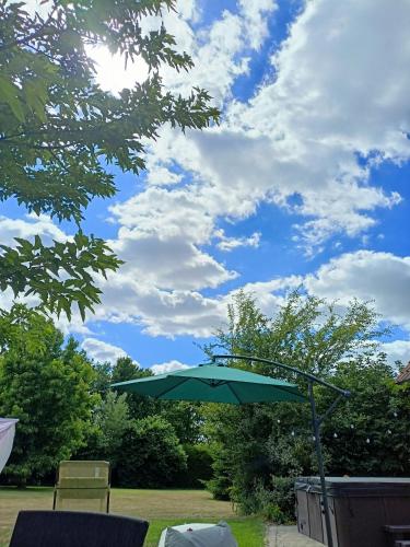 a green umbrella sitting in the middle of a yard at Les chambres du Vert Galant Le lever du soleil in Verlinghem
