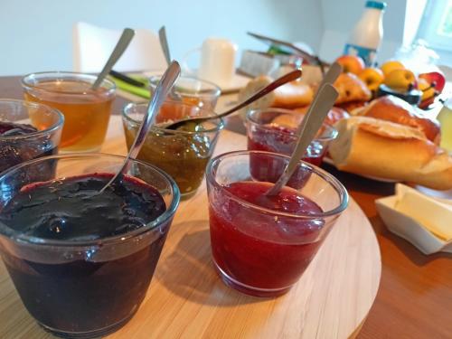 una mesa con cuatro vasos de mermelada y salsa en Les chambres du Vert Galant Le lever du soleil en Verlinghem