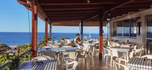 Un uomo seduto in un ristorante con l'oceano sullo sfondo di Paradise a Agia Roumeli