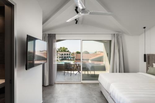 a bedroom with a bed and a view of a balcony at Acharavi Beach Hotel in Acharavi