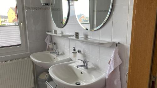 Baño blanco con 2 lavabos y espejo en Ferienwohnung Fresch, en Heiligenhafen