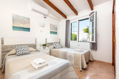 Un dormitorio con dos camas y una ventana. en Villa San Jose by Villa Plus, en Cala'n Porter
