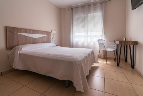 Un dormitorio con una cama y una silla y una ventana. en Hotel Tierra, en Don Benito