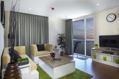 a living room with a couch and a tv at BBG Seaside Luxurious Service Apartment in Bangsaen
