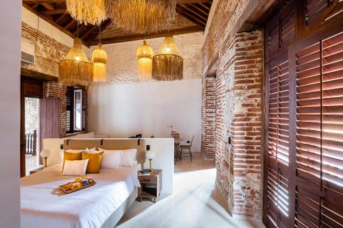 1 dormitorio con cama y pared de ladrillo en Voila Getsemani en Cartagena de Indias