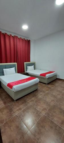 two beds in a room with red curtains at EMAN HOUSE in Salalah