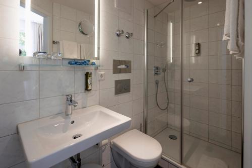 bagno con lavandino, doccia e servizi igienici di Hotel Minerva a Friburgo in Brisgovia