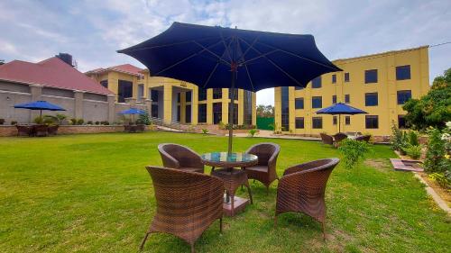 a table with chairs and an umbrella in a yard at Golden Castle Hotel Hoima in Hoima
