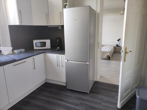 a kitchen with white cabinets and a refrigerator at Ancienne Gare 1er étage in Wasselonne