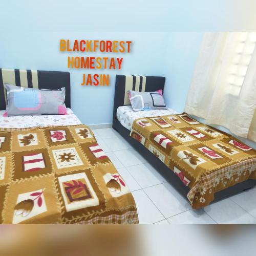 - une chambre avec 2 lits et un panneau indiquant la forêt noire asiatique dans l'établissement HOMESTAY JASIN BLACKFOREST, à Jasin