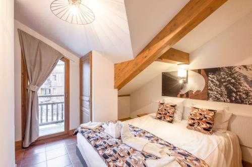 a bedroom with a bed and a large window at Résidence Club mmv Le Hameau des Airelles **** in Montgenèvre