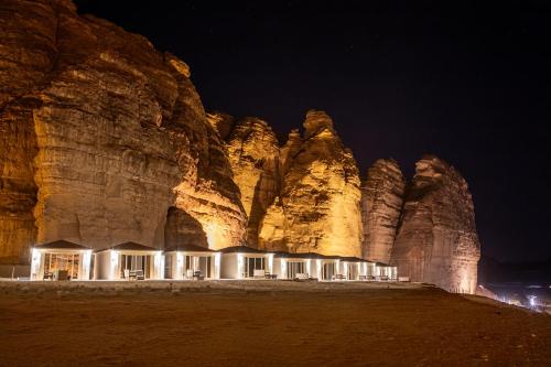 a building in front of a rock wall at night at Shaden Resort in AlUla