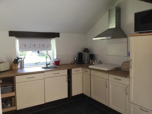 a kitchen with white cabinets and a sink and a window at Landelijk gelegen Huisje op erf in Veeningen