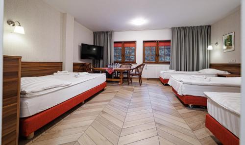 a hotel room with three beds and a table at Leśne Patio in Katowice