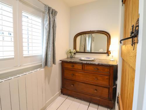 a bathroom with a wooden dresser and a mirror at Tan Y Ddol in Welshpool