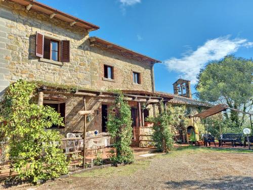 una vieja casa de piedra con vides creciendo en ella en Casa Le Celle en Cortona