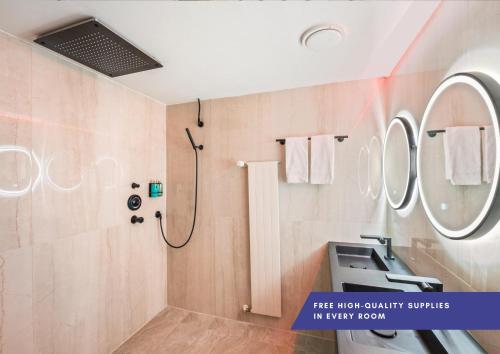 a bathroom with a shower and a sink and mirrors at Becozy Self Check-in Hotel Basel an der Messe in Basel