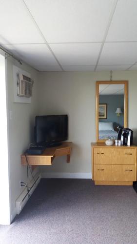 a room with a television and a desk with a mirror at Motel Shantik in Montebello
