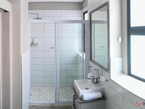 a bathroom with a shower and a sink and a mirror at Next To Apartment Hotel in Pretoria