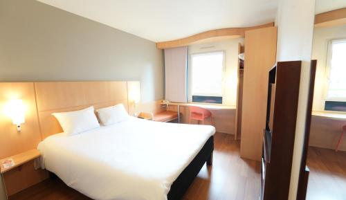a bedroom with a large white bed and two windows at ibis Vitré Centre in Vitré