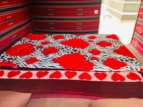 a bed with red roses on a black and white blanket at Bedouin host camp& with tour in Wadi Rum