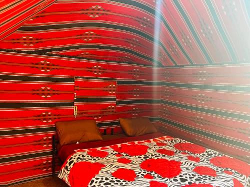 a bedroom with a bed with red and black stripes at Bedouin host camp& with tour in Wadi Rum