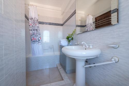 La salle de bains blanche est pourvue d'un lavabo et d'une douche. dans l'établissement Villa Delle Pomelie, à Torre Forte