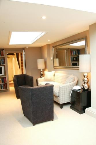 a living room with a couch and a mirror at Manor Green Cottage in Windsor