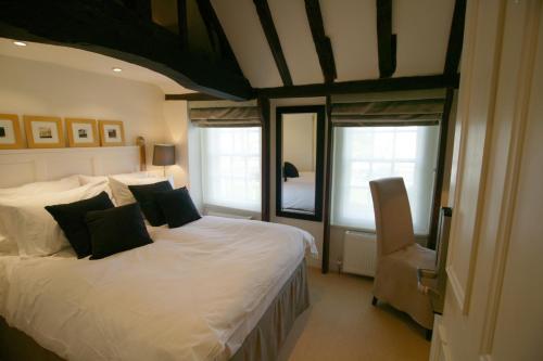 a bedroom with a bed with white sheets and black pillows at Manor Green Cottage in Windsor