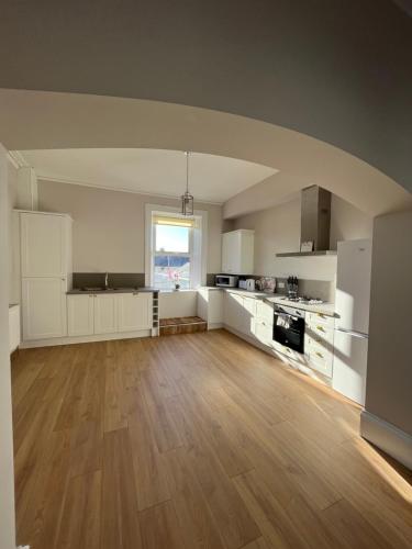 a large kitchen with white cabinets and a wooden floor at 57 Main Street Newcastle Luxury Central Apartment in Newcastle