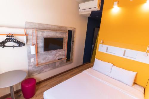 a small room with a bed and a tv at Ibis Budget Lorena - Circuito da Fé in Lorena